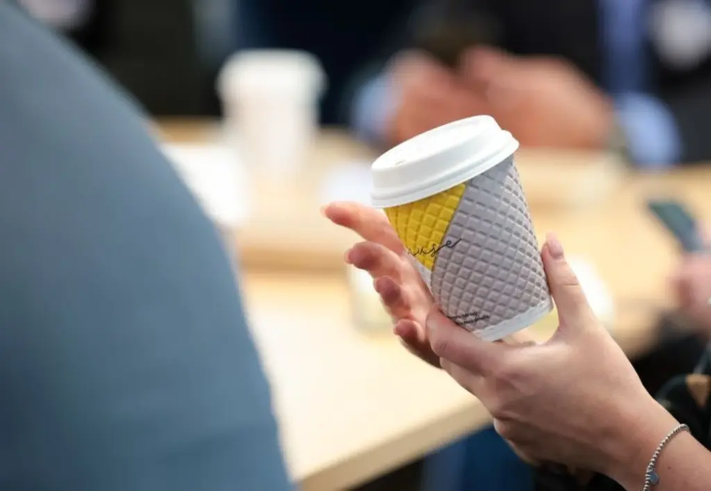 A person holding a coffee cup featuring a striking yellow and black design.