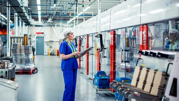 426×240-Leclerc A woman in a factory holds a clipboard, overseeing operations and ensuring quality control.