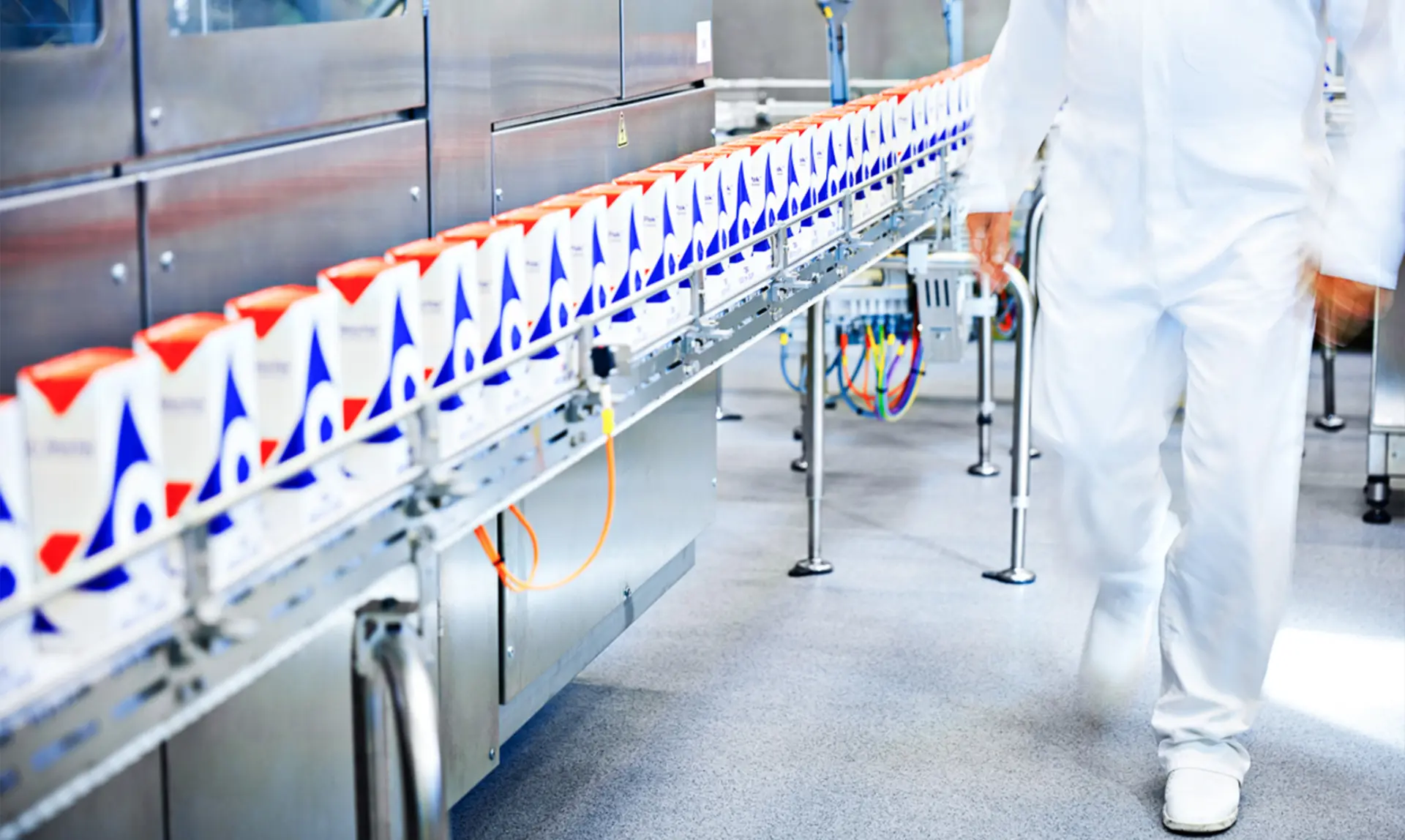 880×526-Eradicating A man in a white uniform walks along a production line, overseeing the manufacturing process.