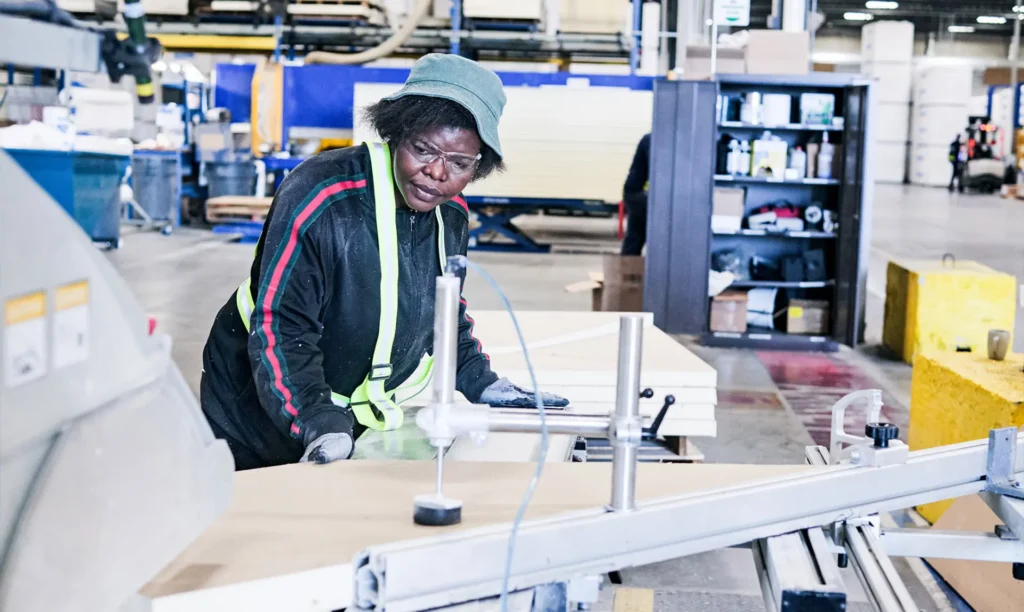 A woman is engaged in machine operation within a factory, demonstrating skill and concentration in her work environment.