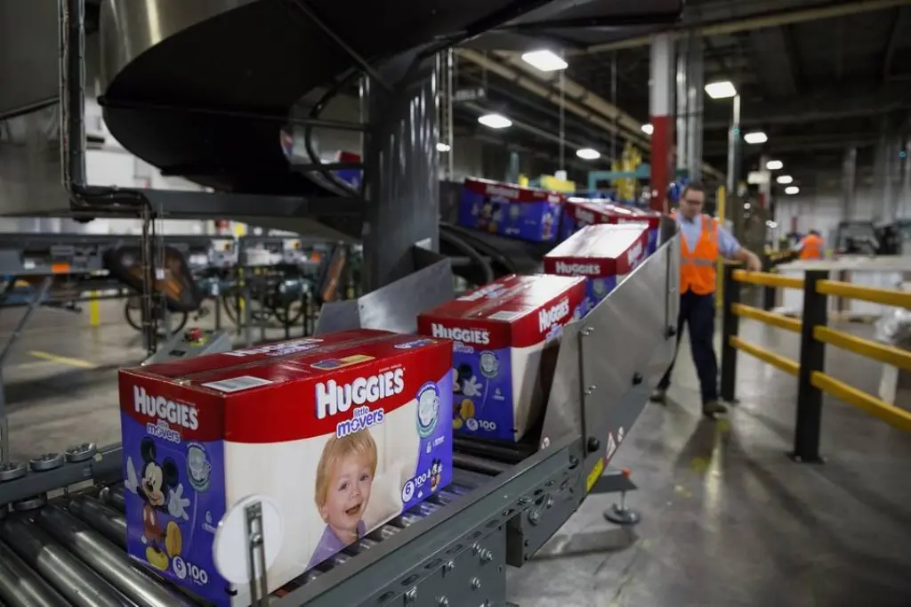 A worker loads diapers onto a conveyor belt in a warehouse setting, preparing for distribution.