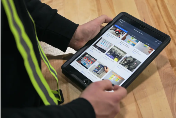 A person holding a tablet viewing poka connected worker application.