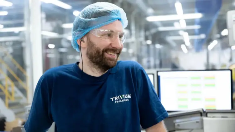 A man wearing a blue shirt and blue hair cap smiles warmly at the camera.