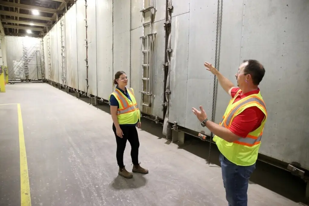 Two individuals in safety vests standing in a spacious warehouse