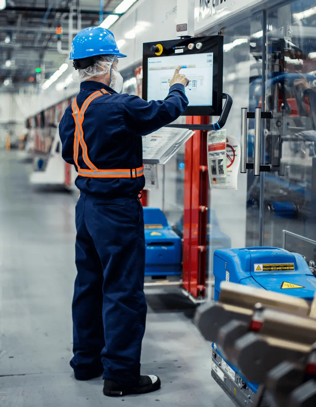 A worker in a factory operating a touch-screen computer to manage tasks and workflow.