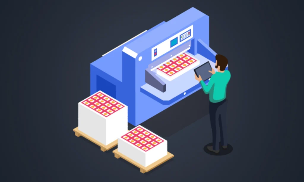 A man stands beside a machine that is actively producing a cardboard box.