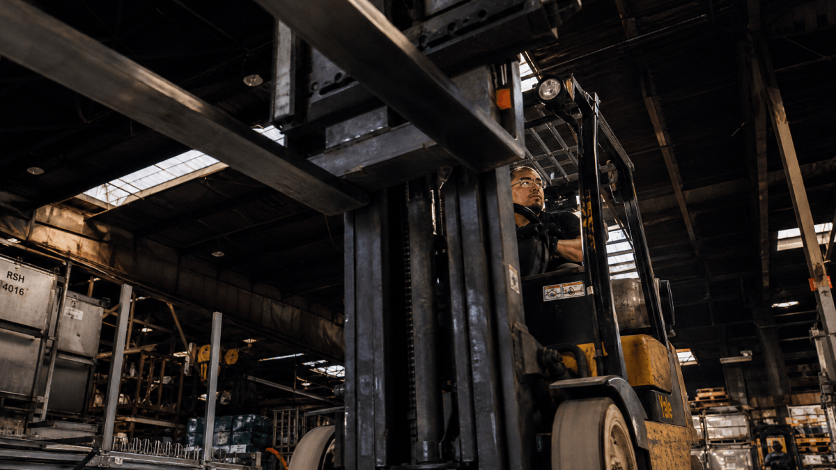 Forklift operator working inside an industrial warehouse.