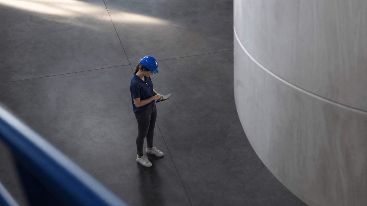A person looking at a mobile tablet on her hand in the middle of a factory floor