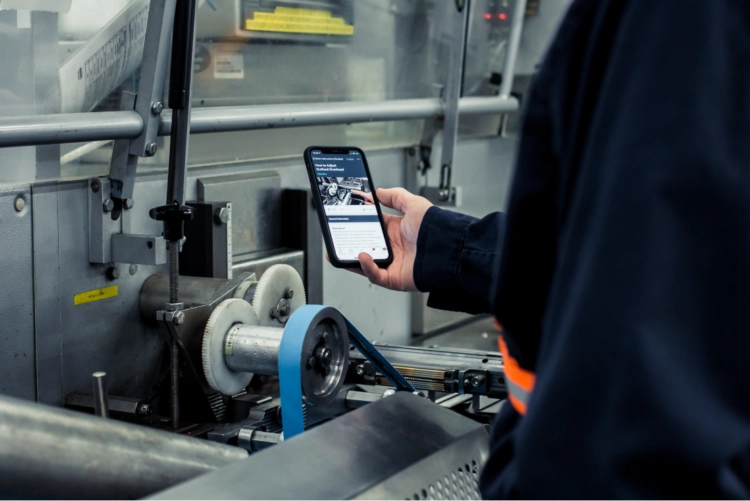 maintenance-factory-worker-1555×370 A person viewing machine instructions on a mobile device